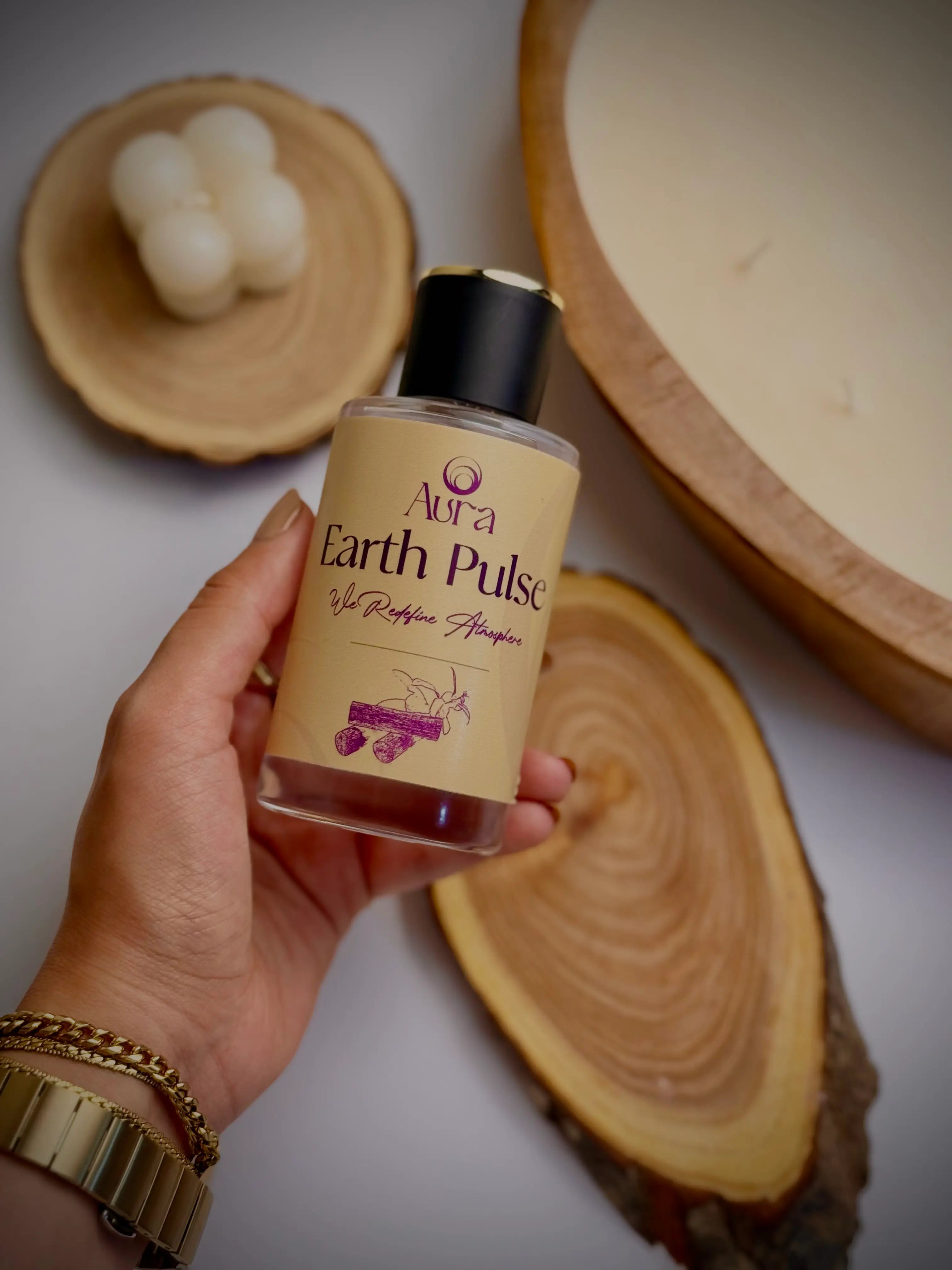 Hand holding a bottle of Aroma Earth Pulse shampoo with wooden and natural product background